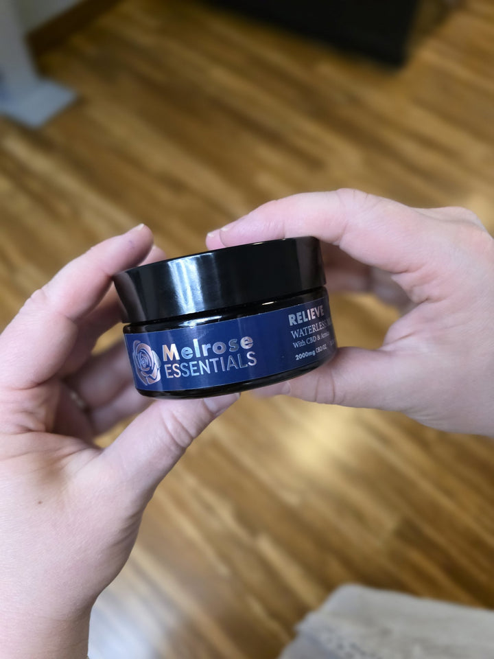 Hands holding a 100 ml jar of Melrose Relieve waterless CBD balm