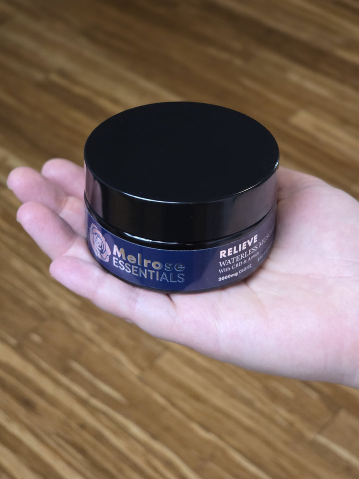 Melrose Relieve waterless CBD balm 100 ml jar held in an open hand, showing the 2,000 mg CBD per oz label