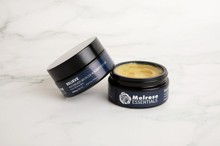 Two jars of Melrose Relieve waterless CBD cream on marble, one open to show the balm