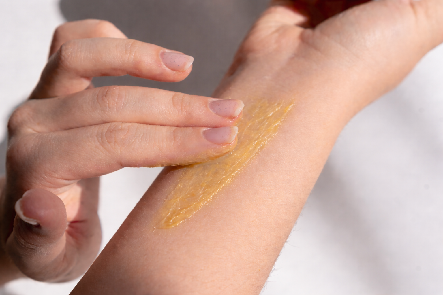 Hand applying a Melrose Essentials Relieve CBD cream arm against a white background