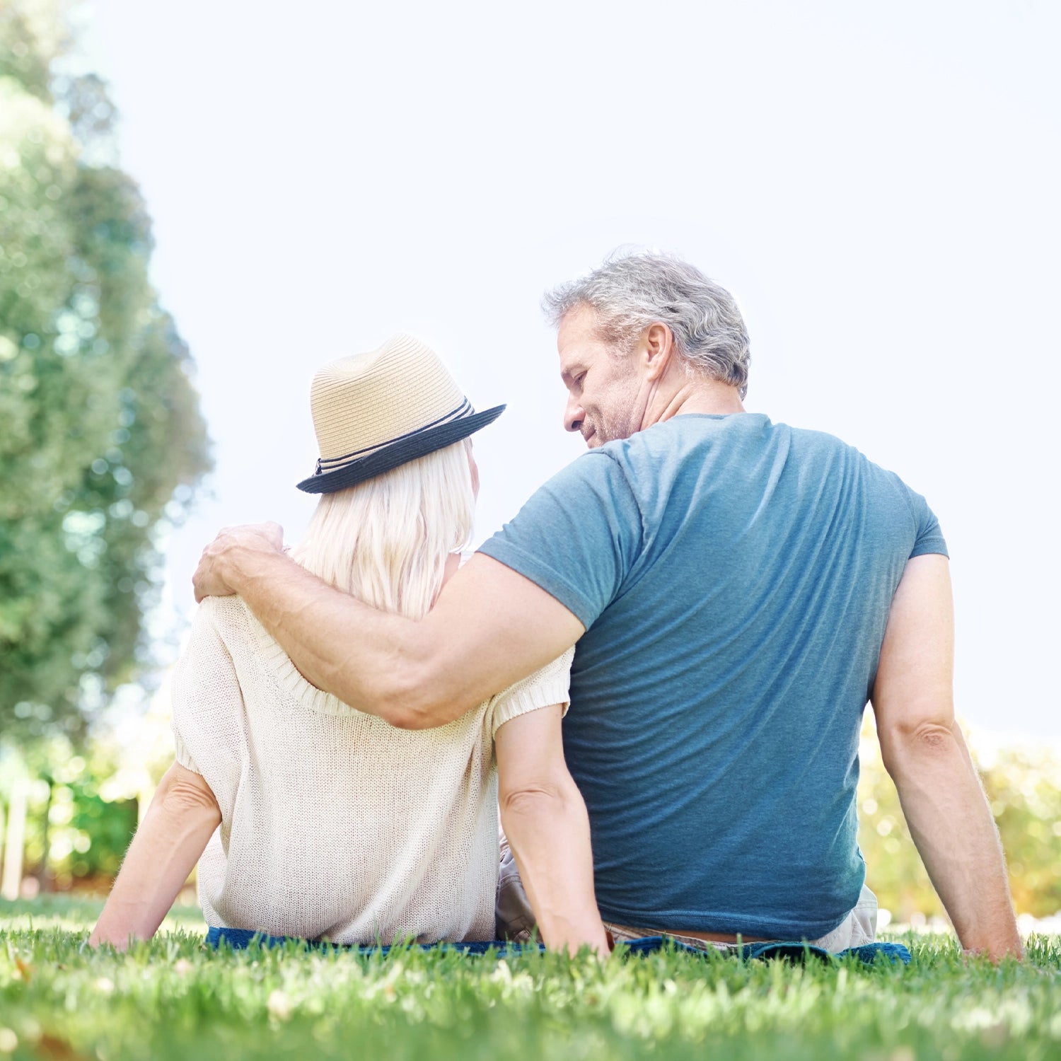 Man and woman sitting on grass in a park, embracing