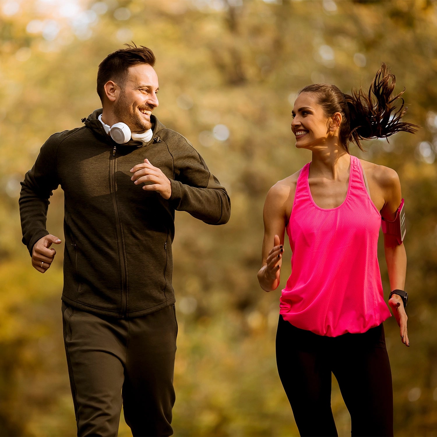 Man and woman jogging outdoors with a blurred natural background