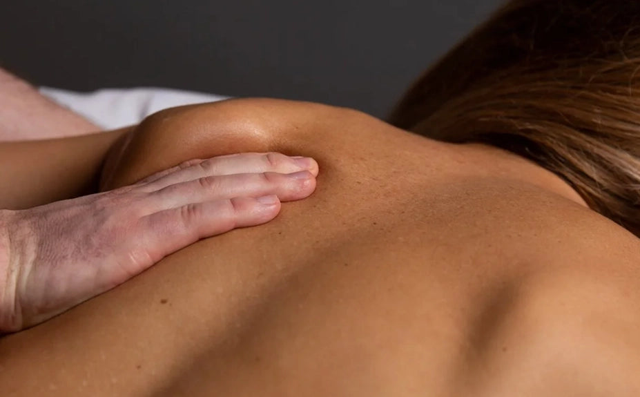 Close-up of a hand massaging a person's back with a neutral background