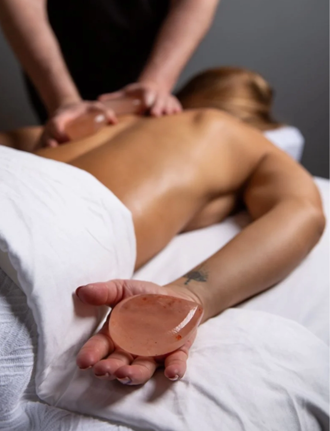 Person receiving a massage with a focus on the hands holding a pink object.
